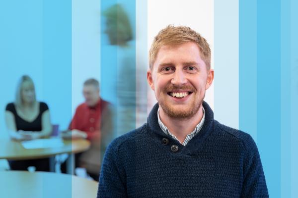 Smart-casual smiling man in meeting room with two people identifying talent